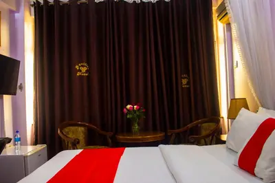 a bedroom with a bed and a table with a vase of flowers at New Hotel Aquiline in Arusha