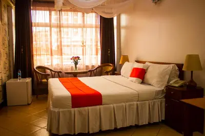 a bedroom with a bed and a table and a window at New Hotel Aquiline in Arusha