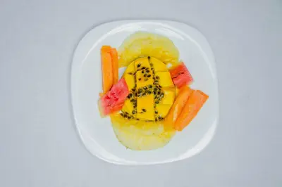 a white plate of food with fruit and vegetables at New Hotel Aquiline in Arusha