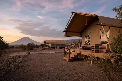 a house with a porch and a mountain in the background at Africa Safari Lake Natron in Mtowabaga