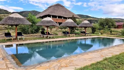 a resort with a pool with chairs and umbrellas at Africa Safari Lake Natron in Mtowabaga