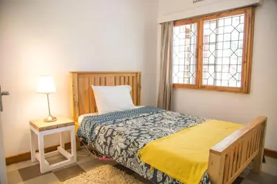 a small bedroom with a bed and a window at Lavender Coffee Farm House in Arusha