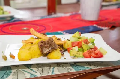 a plate of food with fries and vegetables on a table at Lavender Coffee Farm House in Arusha