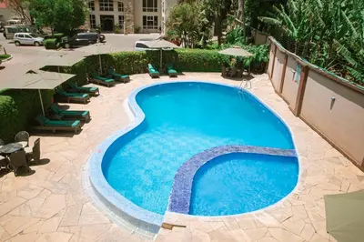 a swimming pool with chairs and umbrellas next to a building at SG Premium Resort in Arusha