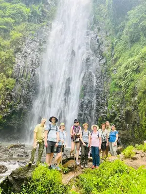 a group of people standing in front of a waterfall at Turaco Homestay in Arusha