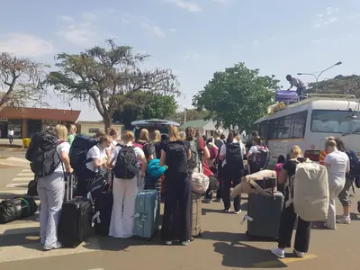 a group of people with luggage standing in front of a bus at Turaco Homestay in Arusha