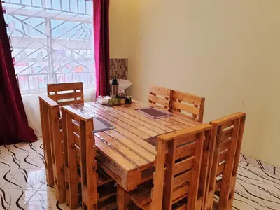 a wooden dining room table with chairs and a window at Turaco Homestay in Arusha