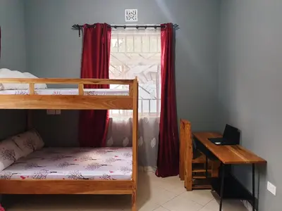 a bedroom with two bunk beds and a desk and a window at Turaco Homestay in Arusha