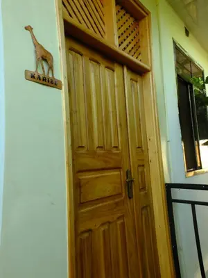 a wooden door with a giraffe sign on it at Enjivai Hostel in Arusha