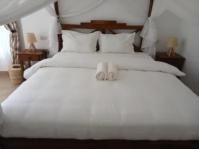 two towels are sitting on a white bed at Bird of Paradise Eco Lodge in Arusha