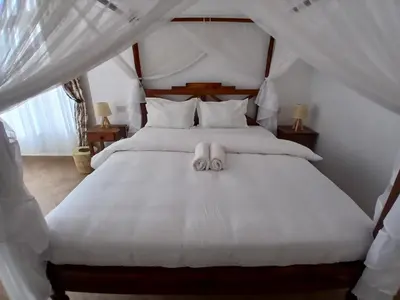 a bedroom with a white bed with two towels on it at Bird of Paradise Eco Lodge in Arusha