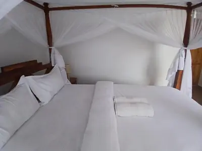 a white bed with white sheets and pillows at Bird of Paradise Eco Lodge in Arusha