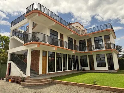 a large white house with balconies and a yard at Bird of Paradise Eco Lodge in Arusha