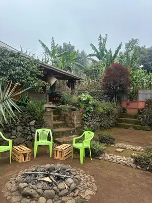 a patio with two green chairs and a fire pit at Mai Kilimanjaro Home Stay in Marangu