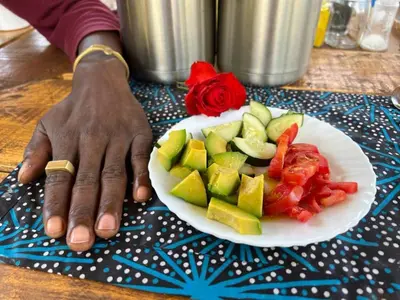 a person with a plate of fruit and vegetables at Mai Kilimanjaro Home Stay in Marangu