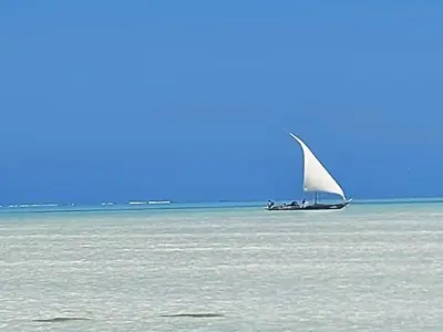 a sailboat on the water with a boat in the ocean at Mai Kilimanjaro Home Stay in Marangu