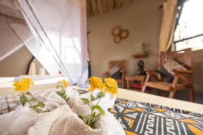 a bedroom with yellow flowers in white vases on a bed at Africa Safari Arusha in Arusha