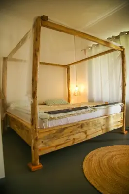 a wooden canopy bed in a room with a rug at Hakuna Woga Inn in Arusha
