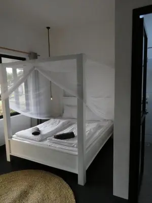 a white bunk bed with white sheets and curtains at Hakuna Woga Inn in Arusha