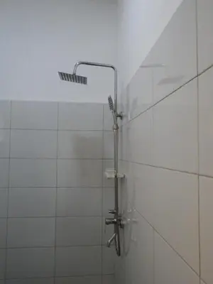 a shower with a shower head on a white tile wall at Hakuna Woga Inn in Arusha