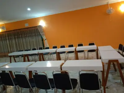 a room with white tables and chairs and an orange wall at Africa Lodge Arusha in Nkoaranga