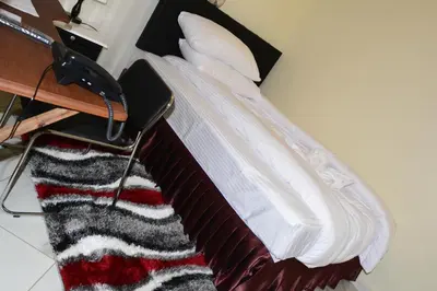 a bed with a pile of pillows and a blanket at Africa Lodge Arusha in Nkoaranga