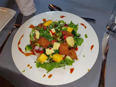 a white plate with a salad on a table at Karanga River Lodge in Moshi