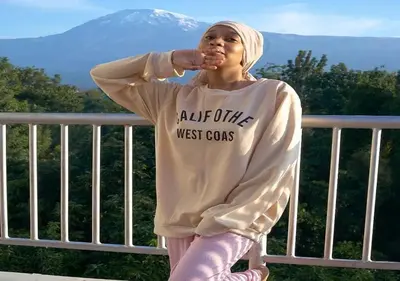 a woman sitting on a railing in front of a mountain at Kilimanjaro White House Hotel in Moshi