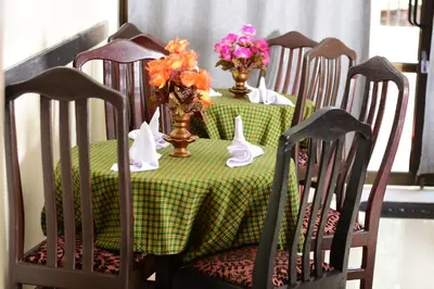 a table with a green table cloth and vases of flowers at Kilimanjaro White House Hotel in Moshi