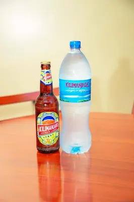 two bottles of beer sitting on a wooden table at Kilimanjaro White House Hotel in Moshi
