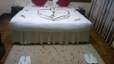 a bed with a wedding cake and a pair of shoes at New Charity Hotel International in Arusha