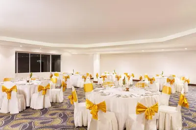 a banquet hall with white tables and yellow bows at Four Points by Sheraton Arusha, The Arusha Hotel in Arusha