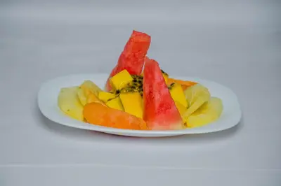 a plate of fruit on a white plate at Maresi Luxury Hotel in Arusha