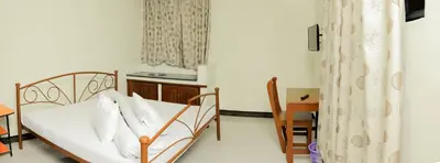 a room with a bed and a table and a kitchen at Maresi Luxury Hotel in Arusha