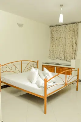 a bedroom with a bed with white sheets and a window at Maresi Luxury Hotel in Arusha
