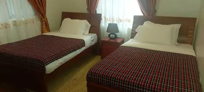 a bedroom with two beds and a lamp on a table at Sumawe Suites in Karatu