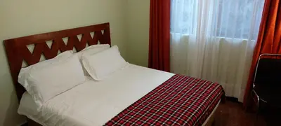 a bed with a checkered blanket and a window at Sumawe Suites in Karatu