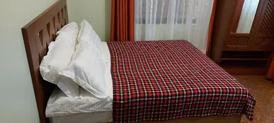 a bed with a checkered blanket and white pillows at Sumawe Suites in Karatu