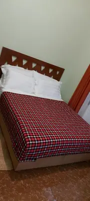 a bed with a red and black plaid blanket and pillows at Sumawe Suites in Karatu