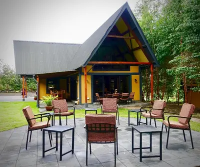 a group of chairs and tables in front of a building at Shamba Lodge Cabin B in Arusha