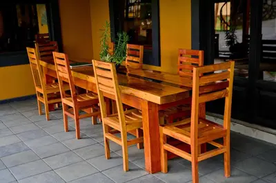 a wooden table and chairs sitting in front of a restaurant at Shamba Lodge Cabin B in Arusha