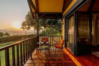 a balcony of a house with a table and chairs at Shamba Lodge Cabin B in Arusha