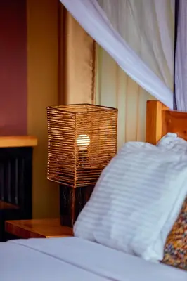 a lamp on a table next to a bed at Shamba Lodge Cabin B in Arusha