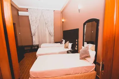 three beds in a hotel room with a mirror at Panone Hotels - King'ori Kilimanjaro Airport in Moshi
