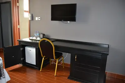a black desk with a chair and a television on a wall at Panone Hotels - King'ori Kilimanjaro Airport in Moshi
