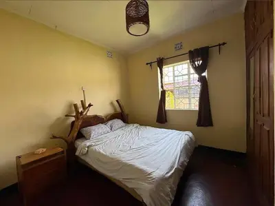a bedroom with a bed and a window at Nguruma house of travellers and tours in Arusha