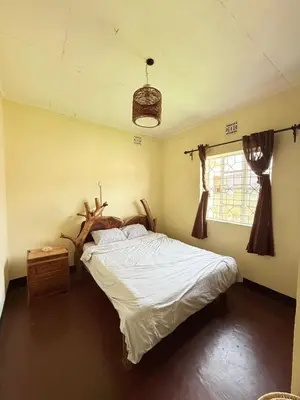 a bedroom with a bed and a tree in it at Nguruma house of travellers and tours in Arusha