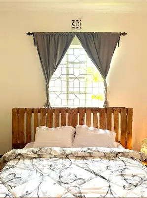 a bed in a room with a window at Nguruma house of travellers and tours in Arusha