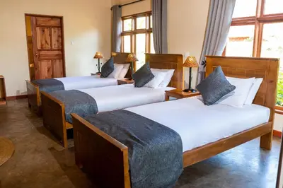 a hotel room with three beds and a window at Ngorongoro Marera Mountain View Lodge in Karatu