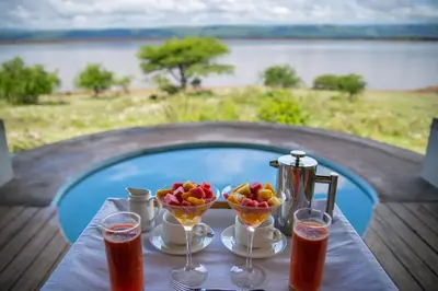 a table with drinks and fruit on a table with a pool at Manyara's Secret in Mto wa Mbu